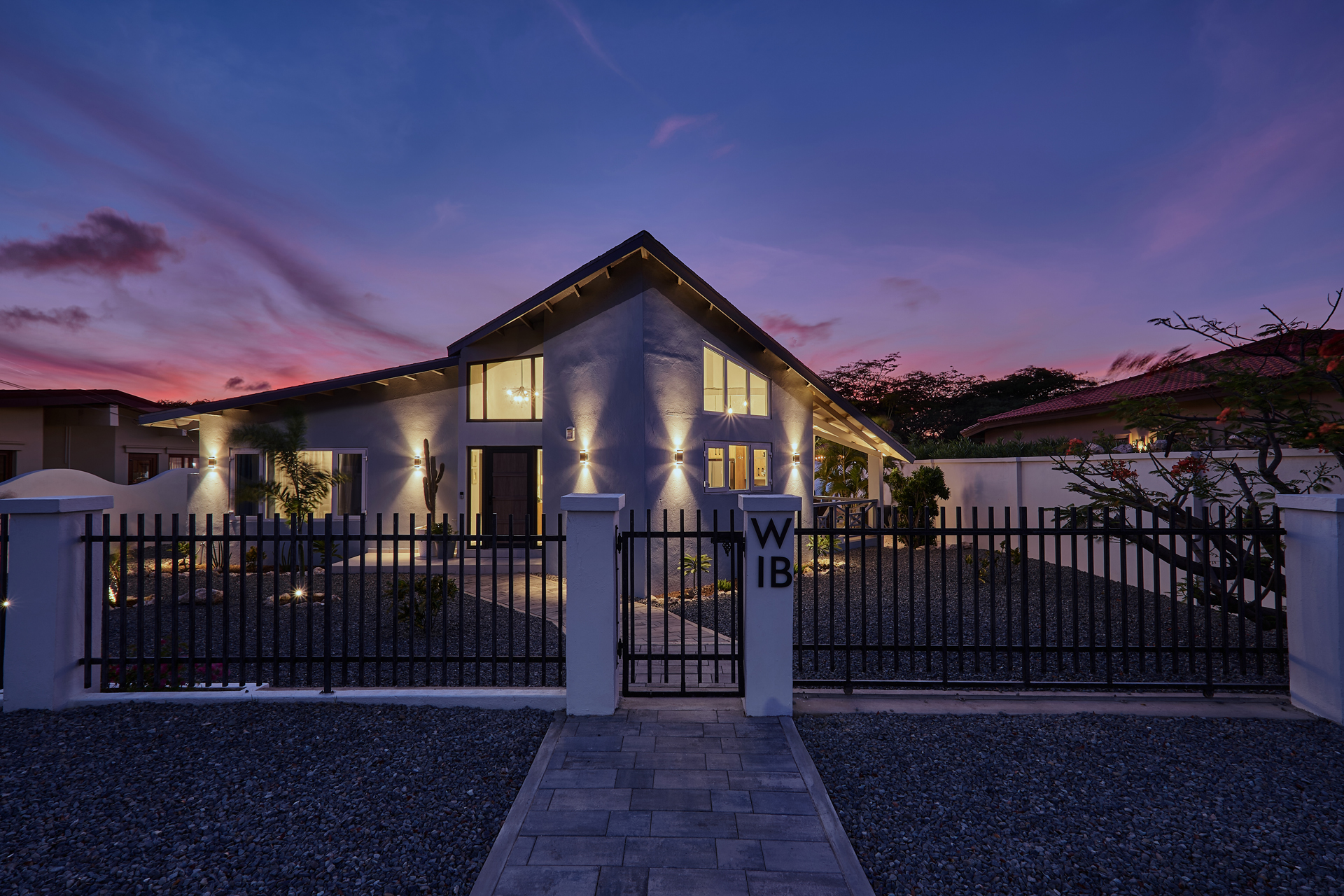 Casa Azul Aruba at twilight, exterior view with warm lights and a pink sunset sky