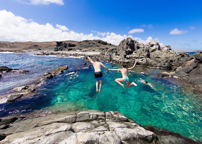Conchi natural pool with swimmers jumping into turquoise water